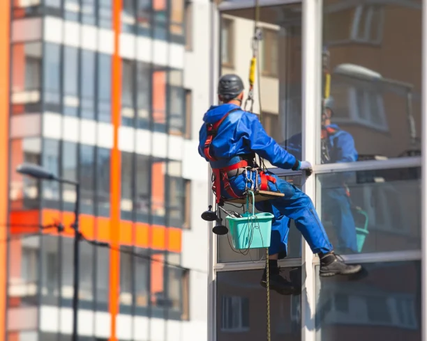 Especialista suspendido frente a una fachada de vidrio
