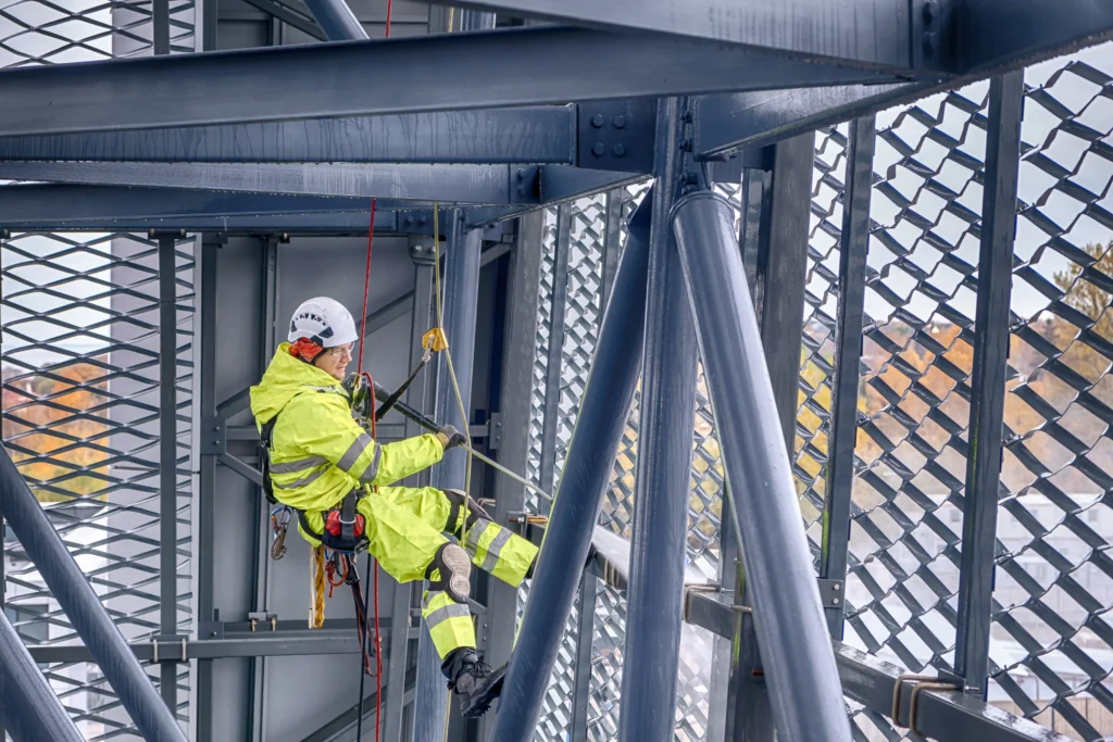 Técnico de trabajos verticales limpiando una fachada acristalada